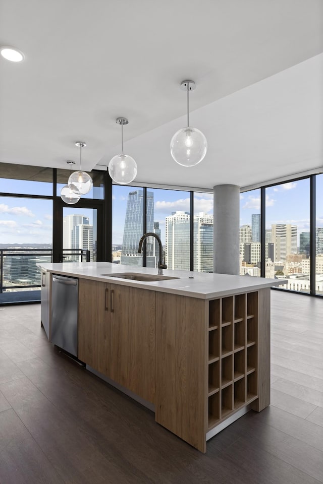 kitchen with a sink, dishwasher, modern cabinets, a city view, and an island with sink