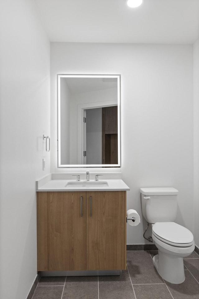 bathroom with toilet, baseboards, vanity, and tile patterned floors