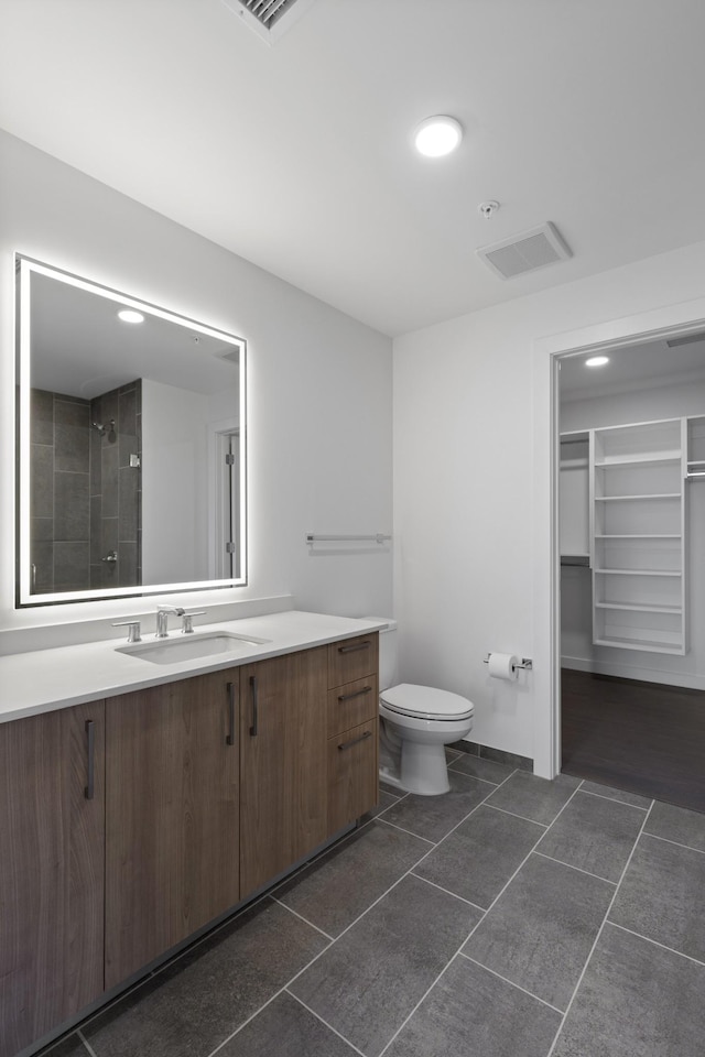 full bath featuring tile patterned floors, toilet, a spacious closet, vanity, and recessed lighting