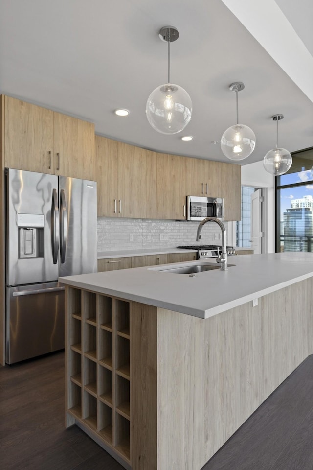 kitchen with appliances with stainless steel finishes, light brown cabinets, a center island with sink, modern cabinets, and light countertops