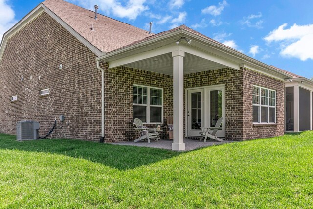 back of house with brick siding, a patio, cooling unit, a yard, and a shingled roof