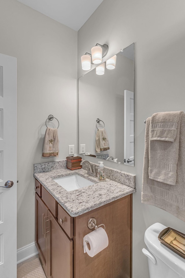 bathroom featuring vanity, toilet, and baseboards