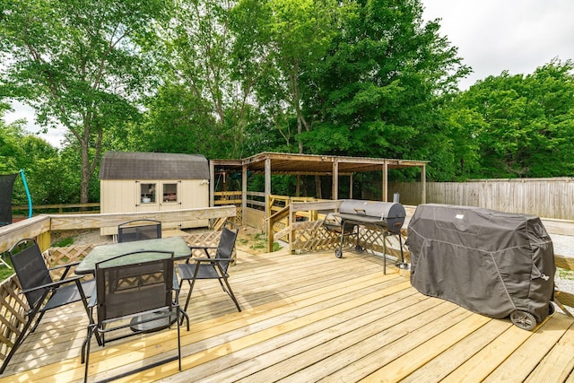 wooden terrace with outdoor dining space, grilling area, a fenced backyard, an outdoor structure, and a storage shed
