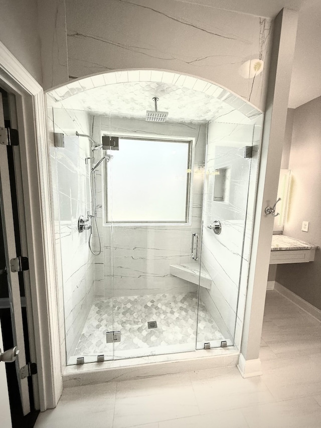full bathroom featuring a marble finish shower and baseboards