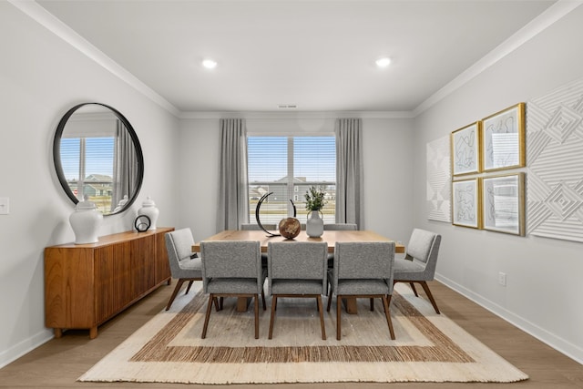 dining room with light wood finished floors, crown molding, baseboards, and recessed lighting
