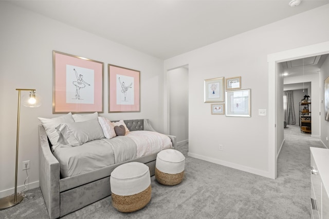 bedroom with attic access, light colored carpet, and baseboards