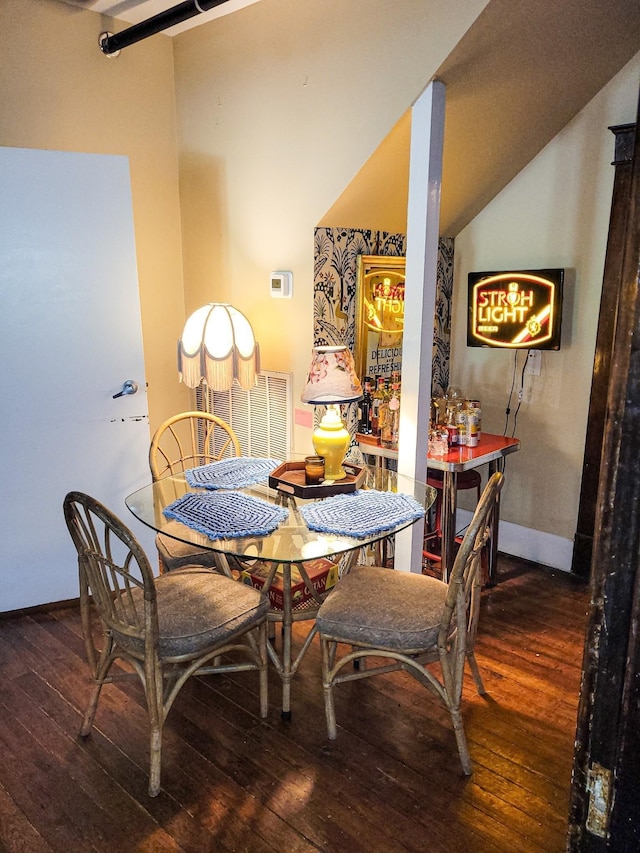 dining space with hardwood / wood-style floors, baseboards, and vaulted ceiling