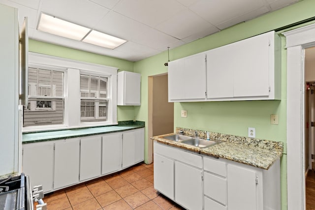kitchen with a sink, white cabinets, a paneled ceiling, and light countertops