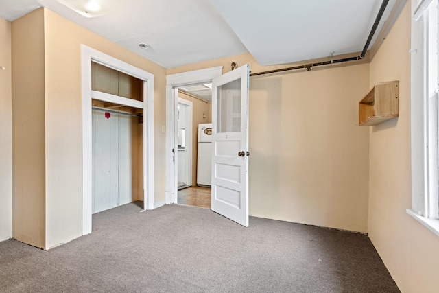unfurnished bedroom featuring freestanding refrigerator, carpet flooring, and a closet