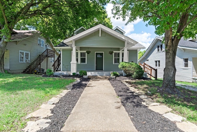 bungalow with a front yard, stairway, and covered porch