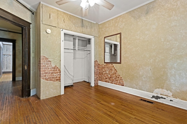 unfurnished bedroom with hardwood / wood-style flooring, ornamental molding, a closet, baseboards, and a ceiling fan