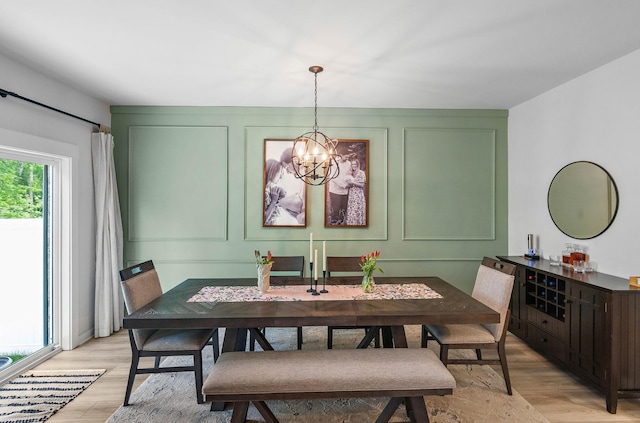 dining area featuring a chandelier, light wood-type flooring, and a decorative wall