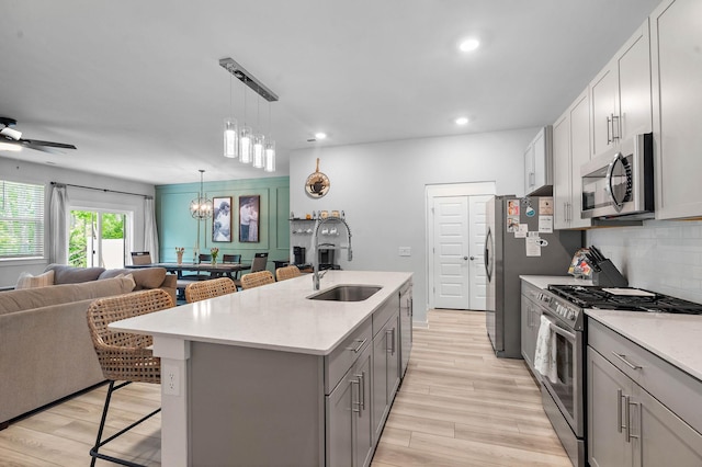 kitchen with appliances with stainless steel finishes, a sink, open floor plan, a breakfast bar, and light wood finished floors