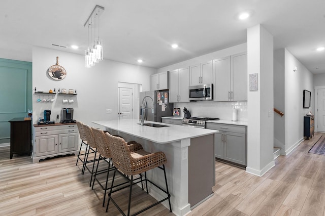 kitchen featuring appliances with stainless steel finishes, backsplash, light wood-style floors, a kitchen breakfast bar, and recessed lighting
