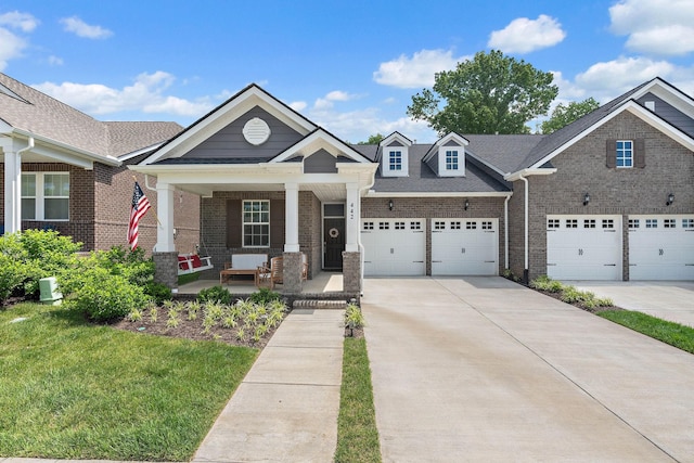 view of front of home with covered porch, concrete driveway, brick siding, and a front lawn