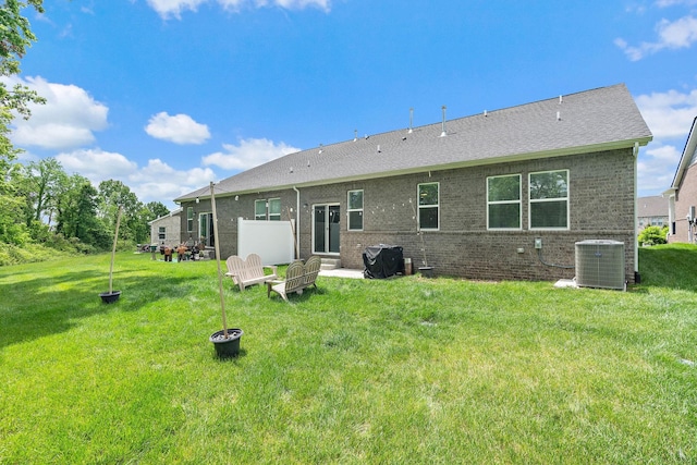 back of property with cooling unit, a yard, and brick siding
