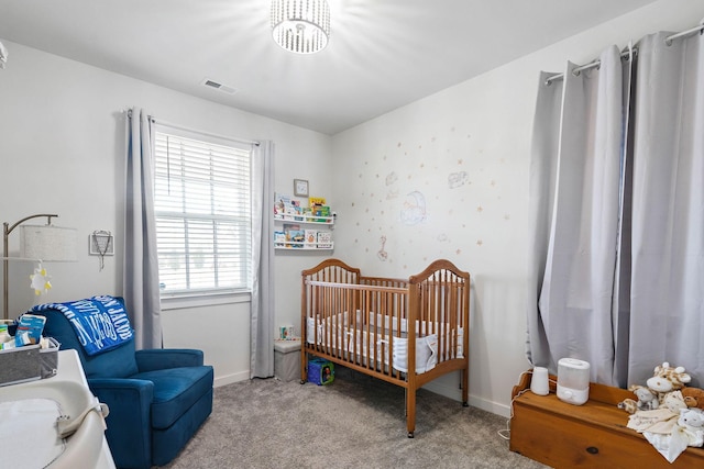 carpeted bedroom featuring a crib and baseboards