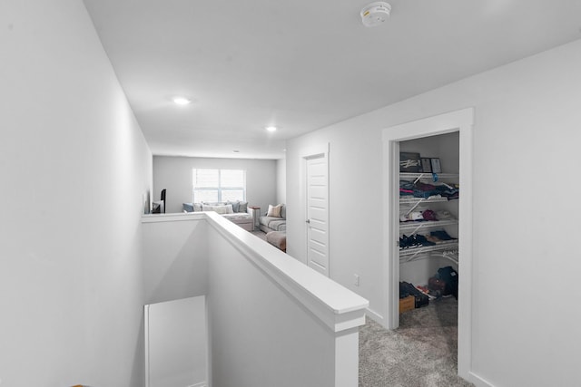 hall with an upstairs landing, light colored carpet, and recessed lighting