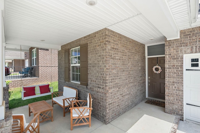 view of exterior entry with brick siding and covered porch