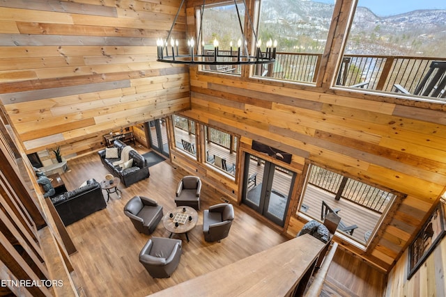 living room with wood walls, a chandelier, a mountain view, healthy amount of natural light, and wood finished floors