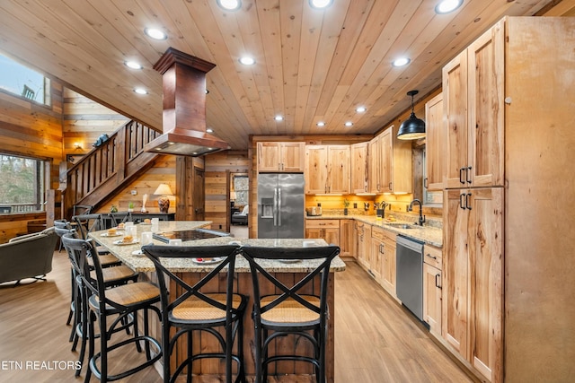 kitchen featuring appliances with stainless steel finishes, a sink, recessed lighting, wood walls, and island range hood