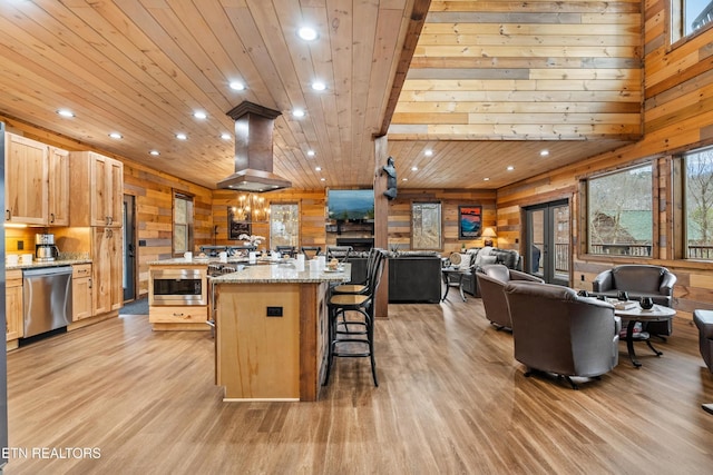 kitchen featuring wooden walls, stainless steel appliances, light wood finished floors, a spacious island, and recessed lighting