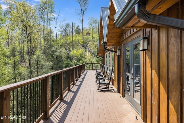 wooden terrace featuring french doors and a wooded view