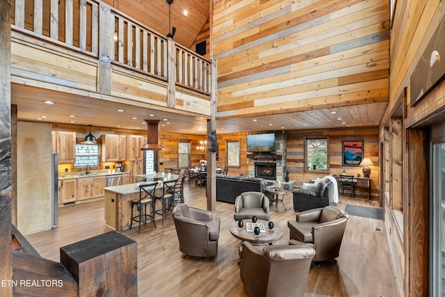 community lobby with high vaulted ceiling, wooden walls, a sink, wooden ceiling, and recessed lighting