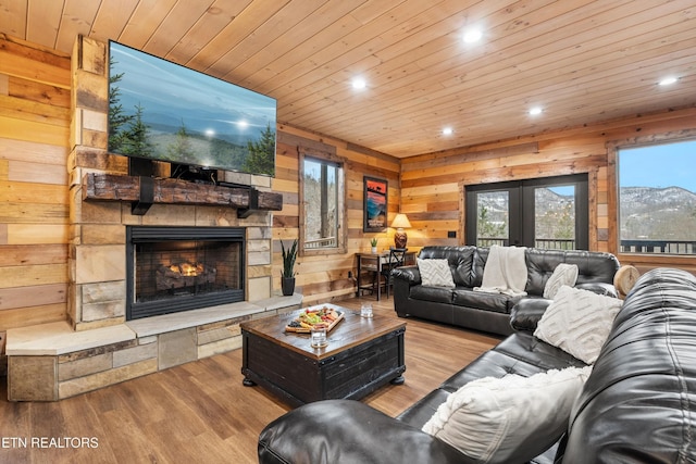 living area featuring recessed lighting, wooden walls, a stone fireplace, wood finished floors, and wood ceiling