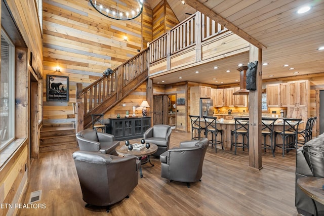 living area with wood walls, stairs, wood finished floors, recessed lighting, and a chandelier