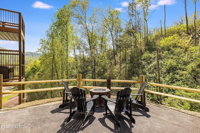 view of patio with a fire pit and a view of trees