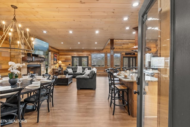 dining space with wood finished floors, recessed lighting, a stone fireplace, wood walls, and wood ceiling