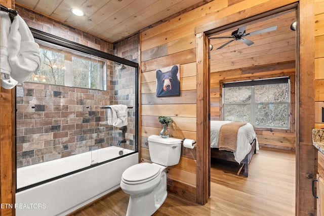 ensuite bathroom with toilet, wood walls, wood finished floors, combined bath / shower with glass door, and wooden ceiling