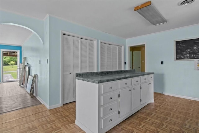 7158 Bahne Rd, Fairview, TN 37062 - kitchen featuring dark countertops, white cabinetry, a center island, baseboards, and arched walkways