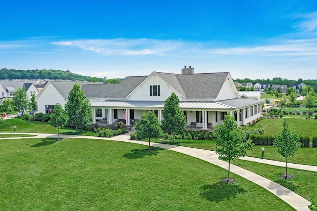 view of front of property featuring a porch, a chimney, a residential view, and a front yard