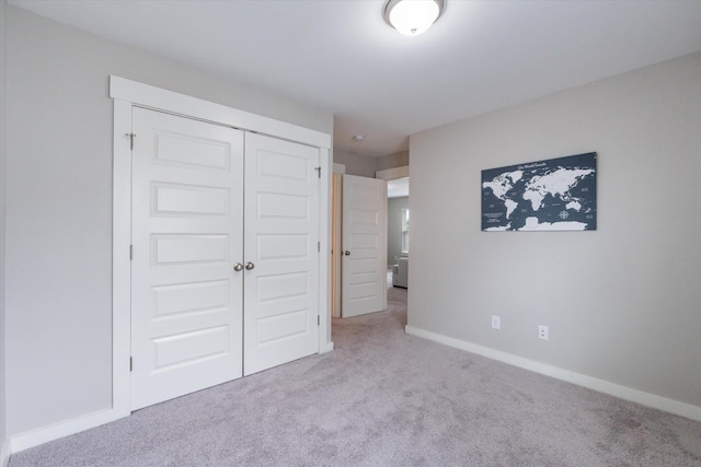 unfurnished bedroom with carpet flooring, a closet, and baseboards