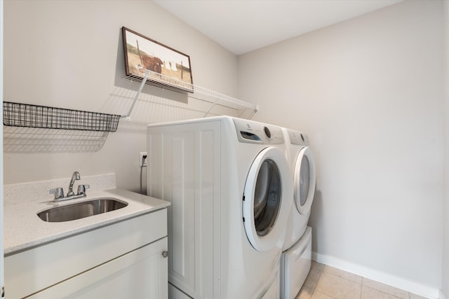clothes washing area with a sink, washer and clothes dryer, light tile patterned floors, and baseboards