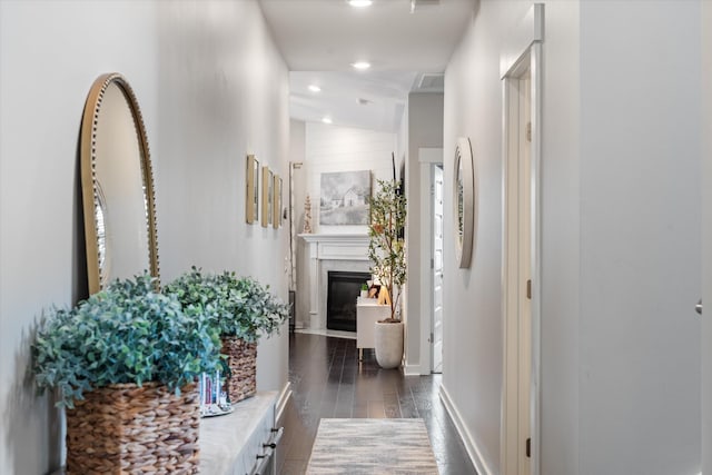 hall featuring dark wood-type flooring, recessed lighting, and baseboards