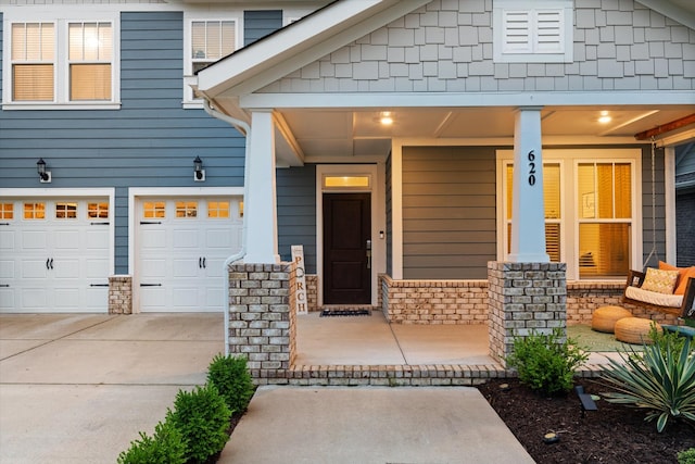 doorway to property featuring a porch, driveway, and a garage