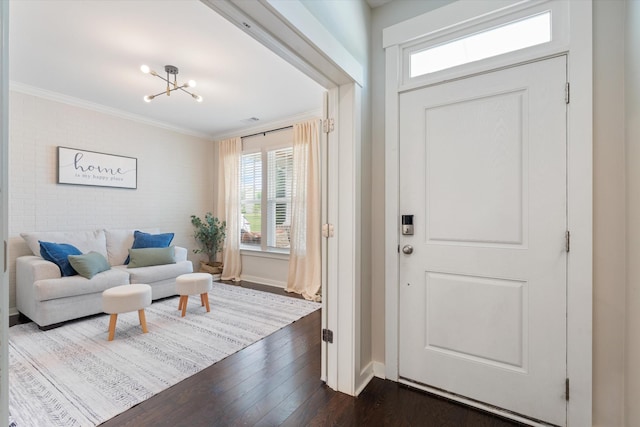 entrance foyer with healthy amount of natural light, ornamental molding, dark wood-style flooring, a chandelier, and baseboards