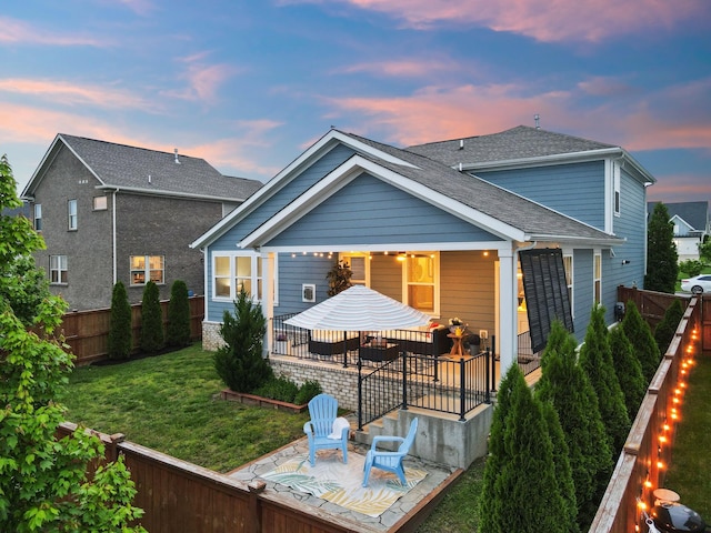 back of house at dusk with a patio and roof with shingles