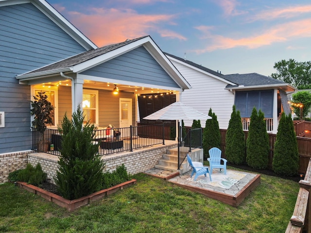 back of property at dusk featuring a patio and a shingled roof