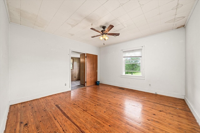 empty room with wood-type flooring, ceiling fan, and baseboards