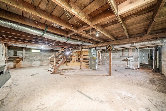 unfinished basement featuring stairs and heating unit