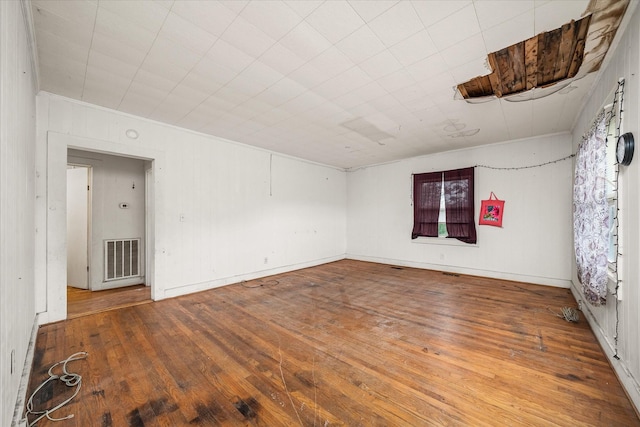 empty room with hardwood / wood-style floors and crown molding