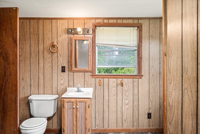 half bath featuring toilet, wood walls, and vanity