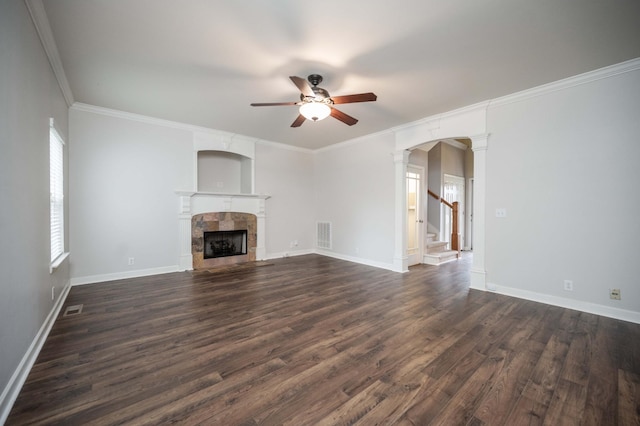 unfurnished living room with a ceiling fan, ornate columns, a tile fireplace, dark wood-type flooring, and baseboards