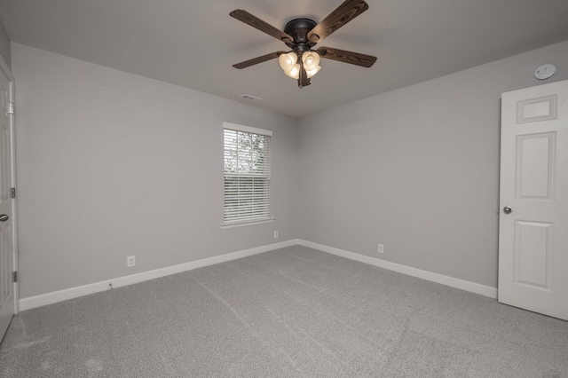 carpeted spare room with a ceiling fan, baseboards, and a smoke detector