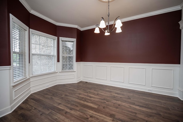 empty room featuring a chandelier, ornamental molding, dark wood-style flooring, and wainscoting