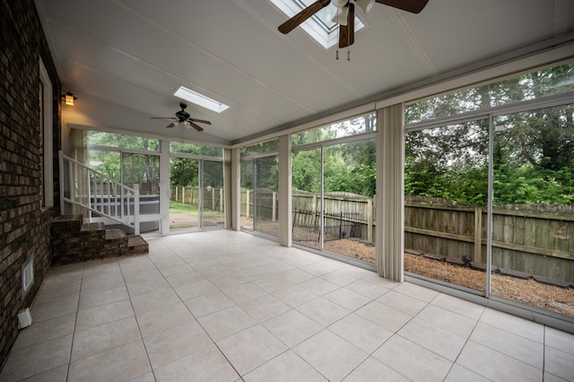 unfurnished sunroom featuring ceiling fan, lofted ceiling, a skylight, and plenty of natural light